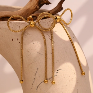 Gros plan de boucles d'oreilles nœud dorées avec chaînes serpent sur un pot en céramique