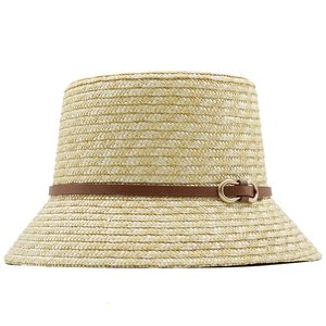 Detail of straw bucket hat featuring a brown leather strap and golden horsebit buckle