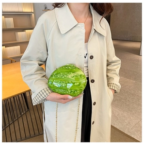Detail of green watermelon acrylic clutch bag with shiny finish and gold chain strap