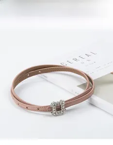 Close-up of leather belt with a square crystal-encrusted buckle on a magazine background
