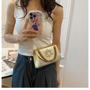 Detail of elegant gold chain crossbody bag with sparkling sunburst rhinestone decoration
