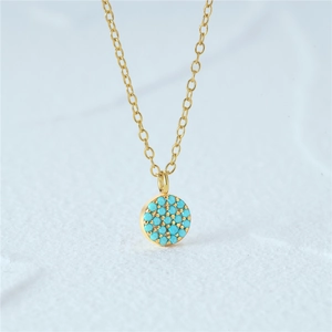 Macro shot of gold sunburst pendant with turquoise inlay on white textured stone