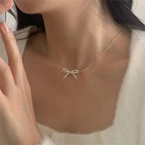 Close-up of elegant gold bow pendant necklace with pearls on a female model