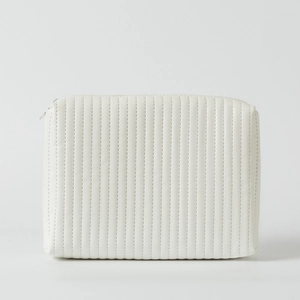 Close-up of a white quilted cosmetic bag featuring sleek vertical stitching and a zipper