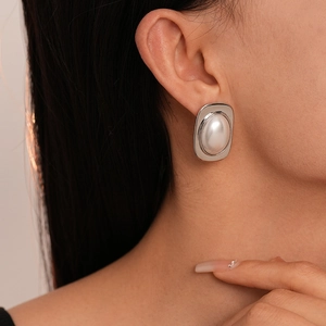 Close-up of geometric square earring with pearl inlay worn by a model