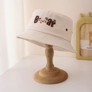 Gros plan sur la broderie ours et les motifs de pattes du chapeau bob beige enfant