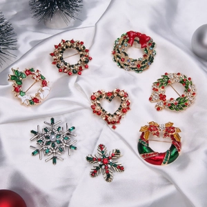Detailed view of assorted Christmas brooches with festive enamel and rhinestones on satin