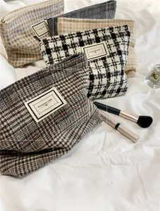 Detail showing various plaid tweed cosmetic bags with woven patterns and zippers