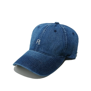 Close-up of R letter embroidery on dark blue denim baseball cap with fine stitching