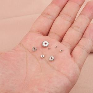 Polished silver stainless steel spacer beads in seven sizes on a hand for jewelry making