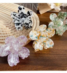 Detailed view of four acetate flower hair claws with marble textures on a wooden tray