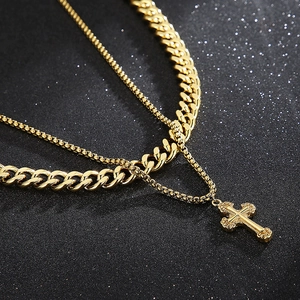 Close-up of golden double-layered Cuban chain necklace with a vintage cross pendant