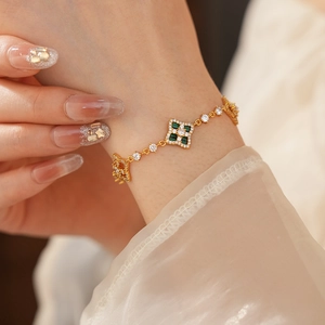 Détail d'un bracelet ajustable en or avec des motifs trèfles verts et blancs sur le poignet