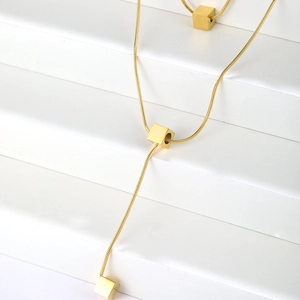 Detailed close-up of golden snake chain necklace with elegant cube pendant charms
