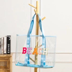 Large clear PVC beach tote bag with blue trim and colorful chenille letter patches