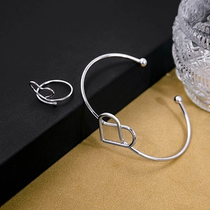 Detailed close-up of hollow heart-shaped silver bracelet and matching ring on elegant stand