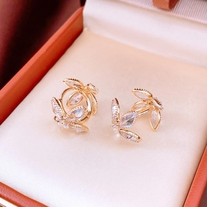 Detail view of gold leaf earrings with marquise-cut zircons on a luxury jewelry box