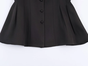 Detailed close-up of pleated hem and button decoration on elegant black blazer jacket