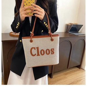 Detail of canvas tote bag with brown leather trim and Cloos lettering on front