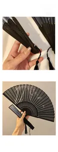 Detail of Chinese silk folding fan featuring green bamboo patterns and a black silk tassel