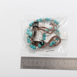 Detailed view of turquoise bead necklace with metal accents and ruler for scale reference