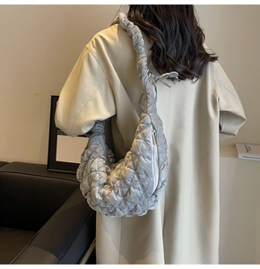 Quilted crescent cloud bag in cold grey shown as a stylish crossbody on a trench coat