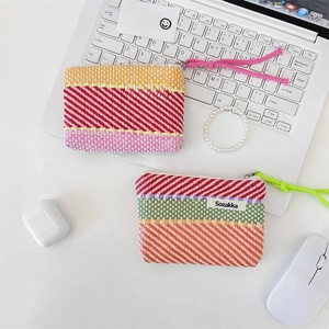 Close-up of contrast stripe and checkerboard woven cosmetic pouches on a white desk