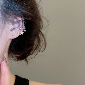 Detailed view of gold star-shaped ear cuff with zircon crystals worn on ear