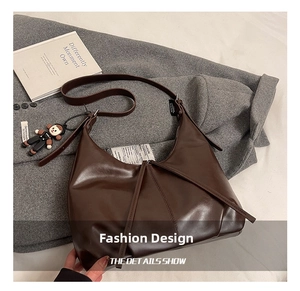 Detailed close-up of dark brown hobo bag with pleated leather texture and cute charm