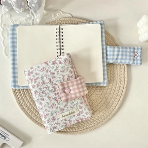 Detail of floral cloth notebook cover with blue check pattern and heart button