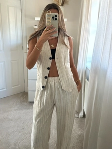Detail of cream striped vest and high-waist trousers set with cotton linen texture