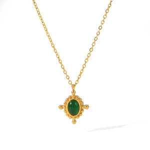 Detailed shot of vintage gold cross necklace with emerald green oval gemstone pendant