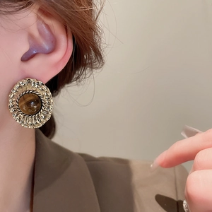 Close-up of model wearing vintage oval faux tiger eye stud earrings with gold-tone base