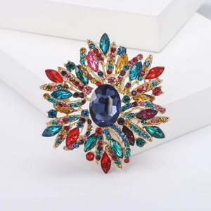 Detail einer goldenen Vintage-Brosche mit großem blauem Kristall und bunten Strasssteinen
