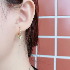 Vue rapprochée d'une boucle d'oreille papillon dorée avec cristaux sur modèle