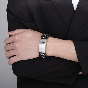 Men's woven leather bracelet with polished stainless steel clasp on a suit sleeve