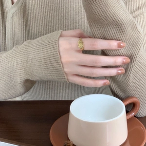 Close-up of a vintage oval gold signet ring with engraved details on a model's finger