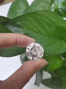 Close-up of a brilliant round cut Moissanite stone showing rainbow fire on a leaf