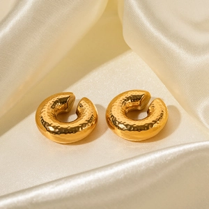 Detailed view of 18K gold plated stainless steel textured hoop earrings on beige silk