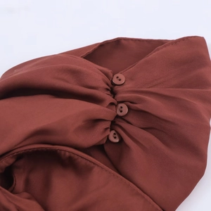 Détail d'une robe midi marron avec texture plissée et trois petits boutons assortis