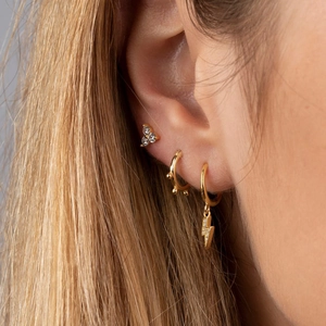 Macro shot of gold-plated lightning bolt hoop earrings with cubic zirconia stud detail