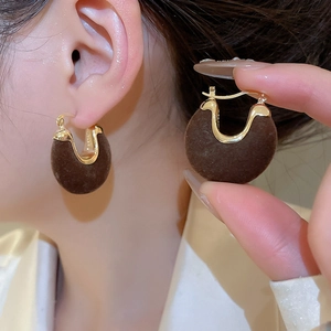 Detail of dark brown flocked U-shaped hoop earring with polished gold-tone metal trim