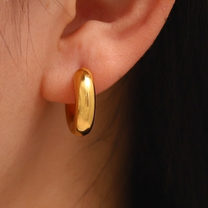 Elegant gold hollow C-shaped earrings in polished titanium steel worn by a model