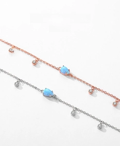 Détail de bracelets en argent et or rose avec opale goutte et breloques en CZ