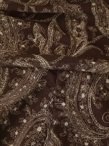 Close-up of deep brown chiffon fabric featuring pleated bohemian paisley floral patterns