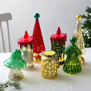 Miniature glass Christmas tree and candle lights with warm LED glow on snowy surface