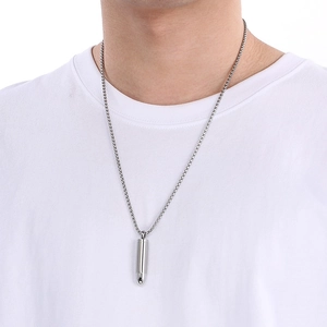 Close-up of a men's silver bullet pendant necklace worn on a white t-shirt