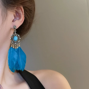 Détail de boucles d'oreilles bohèmes à plumes bleues et détails argentés vintage