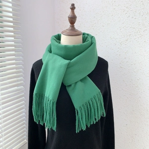 Detail of green solid color scarf with soft fringes showing cashmere-like texture