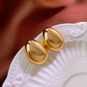 Vue rapprochée des boucles d'oreilles dorées en forme de goutte sur plat céramique